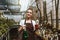 Happy young woman standing in greenhouse near plants