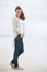 Happy young woman in sweater enjoying lonely beach