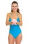 Happy young woman in swimsuit giving piggy bank