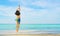 Happy young woman in swimsuit jumping at sand beach. Relaxing and enjoying holiday at tropical paradise beach with blue sky