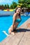 Happy young woman in swimsuit posing in hotel pool. Attractive slim lady with smooth skin smiling in water pool