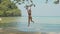 Happy young woman swinging on rope at beautiful beach