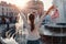 Happy young woman tourist looks at fountain. Summer travel. Vacation and holidays concept