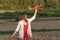 Happy young woman with toy airplane in hands in middle of wheat field, in red dress and white shirt Concept of cheap air travel