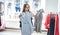 Happy young woman trying on various brand jackets in the shopping mall