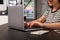 Happy young woman using laptop at table in hostel dining room