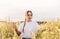 Happy young woman walking in yellow field on summer day