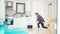 A happy young woman is washing the floor with mop and dancing in the kitchen