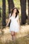 Happy young woman in white dress walking in nature