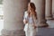 Happy young woman in white jacket with diary walks looking away