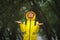 Happy young woman in yellow raincoat under rain