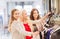 Happy young women choosing clothes in mall