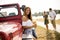 Happy young women drinks cider from the bottle by the convertible car