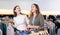 Happy young women holding winter jumpers and sweaters on racks during shopping in a boutique