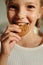 Happy youthful girl biting fresh tasty homemade cookie of round shape