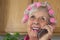 HappySenior Woman in Pink Curlers on Her Cell Phon