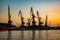 Harbor cargo cranes on sunset sky background