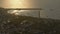 Harbor by coast town with boats separated from sea by breakwater in sunset glow