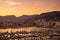 Harbor with dozens of sailing yacht boats and boulevard and mountains in the background during a beautiful sunset on the French