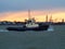 Harbor tug makes its way up the river back to port against an orange sunset