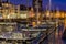 The harbor of vlissingen at night with many docked boats, decorated boats with lights, lighted city buildings with water, popular