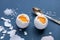 Hard-boiled eggs on a blue pastel background, half peeled, next to it are shells, salt and a spoon. The concept of a