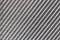 Hard diagonal shadows on grey textured wall from a window roller shutter or blinds. Attractive abstract composition