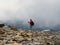 Hard hiking trail. Foggy day in the mountains. Activities woman climb to the top of a misty stone hill. Solo climbing and