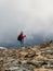 Hard hiking trail. Foggy day in the mountains. Activities woman climb to the top of a misty stone hill. Solo climbing and