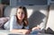 Hard light portrait of cute tween girl lying on sofa with book looking at camera with funny shadow on couch.