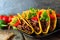 Hard shelled tacos with ground beef, vegetables and cheese, close up scene