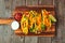 Hard shelled tacos with ground beef, vegetables and cheese, top view on a wood background