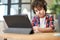 Hard work and dedication. Focused latin american school boy wearing headphones, making notes, using digital tablet while