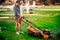 hard working gardener using lawnmower and cutting grass