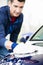 Hard-working man polishing car with white microfiber mitt