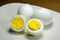 Hardboiled eggs with one cut in half on a plate at the kitchen table