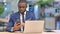 Hardworking African Businessman using Smartphone and Laptop in Office