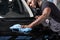 Hardworking black auto mechanic cleaning car surface