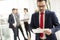 Hardworking businessman dressed in suit standing in modern office and using tablet