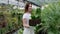 Hardworking farmer woman in a greenhouse holding box with flower pots. Home gardening