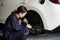 Hardworking female mechanic changing car wheel in auto repair workshop. Oxus