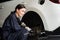 Hardworking female mechanic changing car wheel in auto repair workshop. Oxus