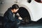 Hardworking female mechanic changing car wheel in auto repair workshop. Oxus