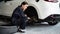 Hardworking female mechanic changing car wheel in auto repair workshop. Oxus