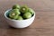 Hardy kiwi fruits or kiwi berry in ceramic bowl on table