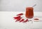 Harissa in a glass jar with a spoon and pods of red hot pepper on a white background. horizontally