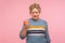 Harmful sweet dessert. Portrait of unhappy woman in sweater holding doughnut, looking at donut with frustration