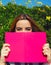 Ð¡harming young woman with pink book held up close to her face