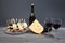 Harmonious composition bottle of red wine with two glasses, cheese, a bunch of grapes. Isolated on gray background