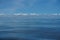 Harmony background scene of gradient blue sky horizon and low raining white cloud above deep blue sea water ripple freezing motion